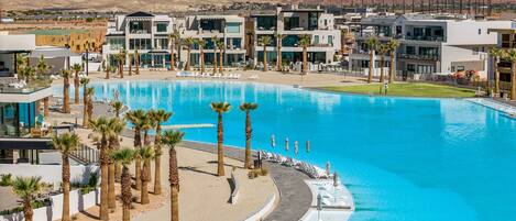 Un resort con una gran piscina, palmeras y edificios modernos.