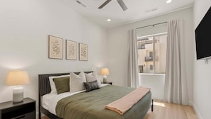 A modern bedroom with a bed, bedside tables, and a window with curtains. - Splash And Swing 6 Bedroom Townhouse (St. George)