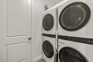 A laundry room with three stacked front-loading washing machines. - Splash And Swing 6 Bedroom Townhouse (St. George)