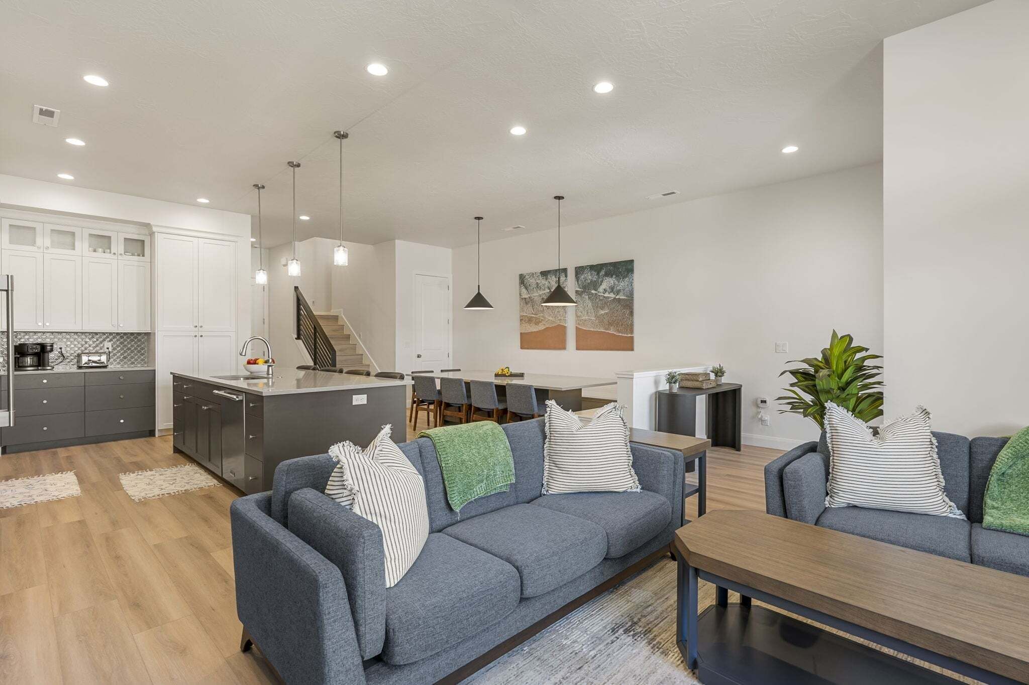 Una cocina moderna con armarios blancos, un comedor con mesa y sillas, y una sala de estar con sofá y mesa de centro.