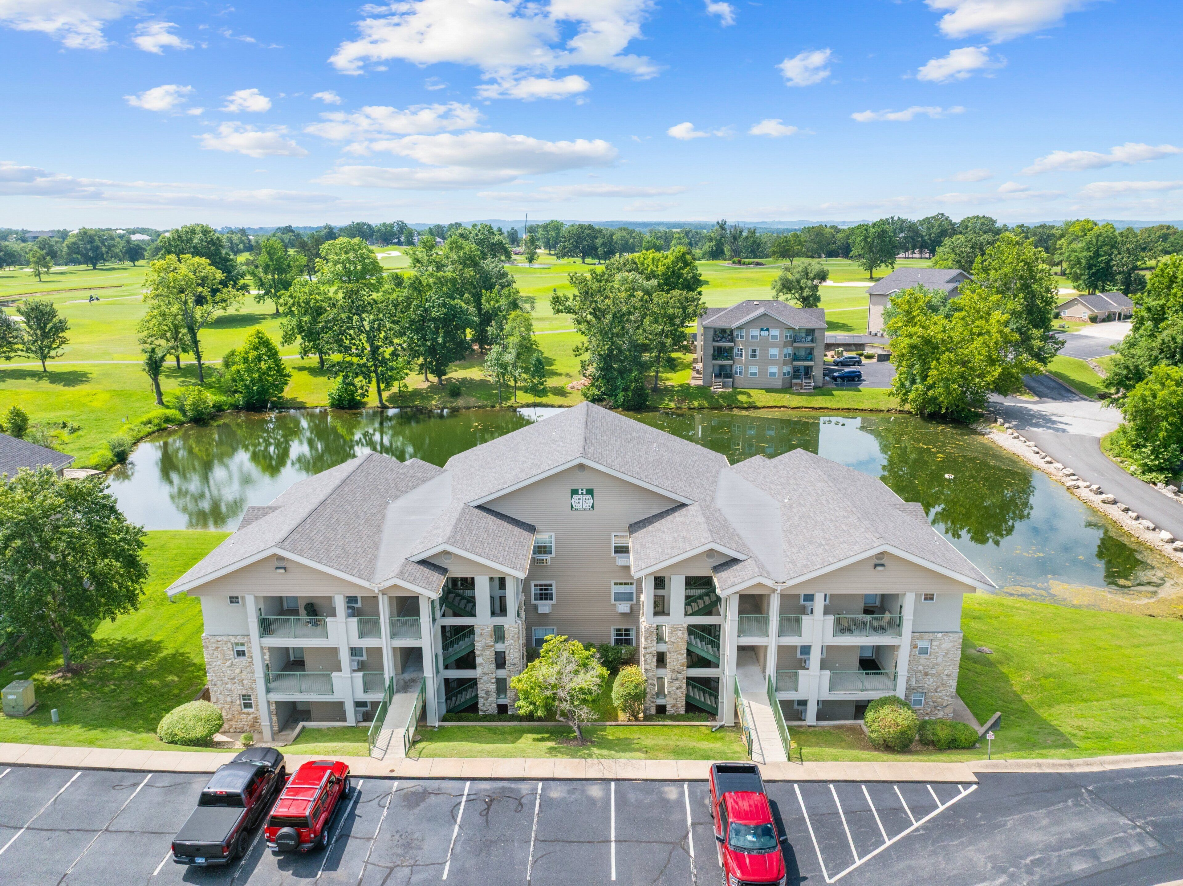 Un hôtel à plusieurs étages doté d’une cour intérieure, d’un parking et offrant une vue sur un terrain de golf et un lac.