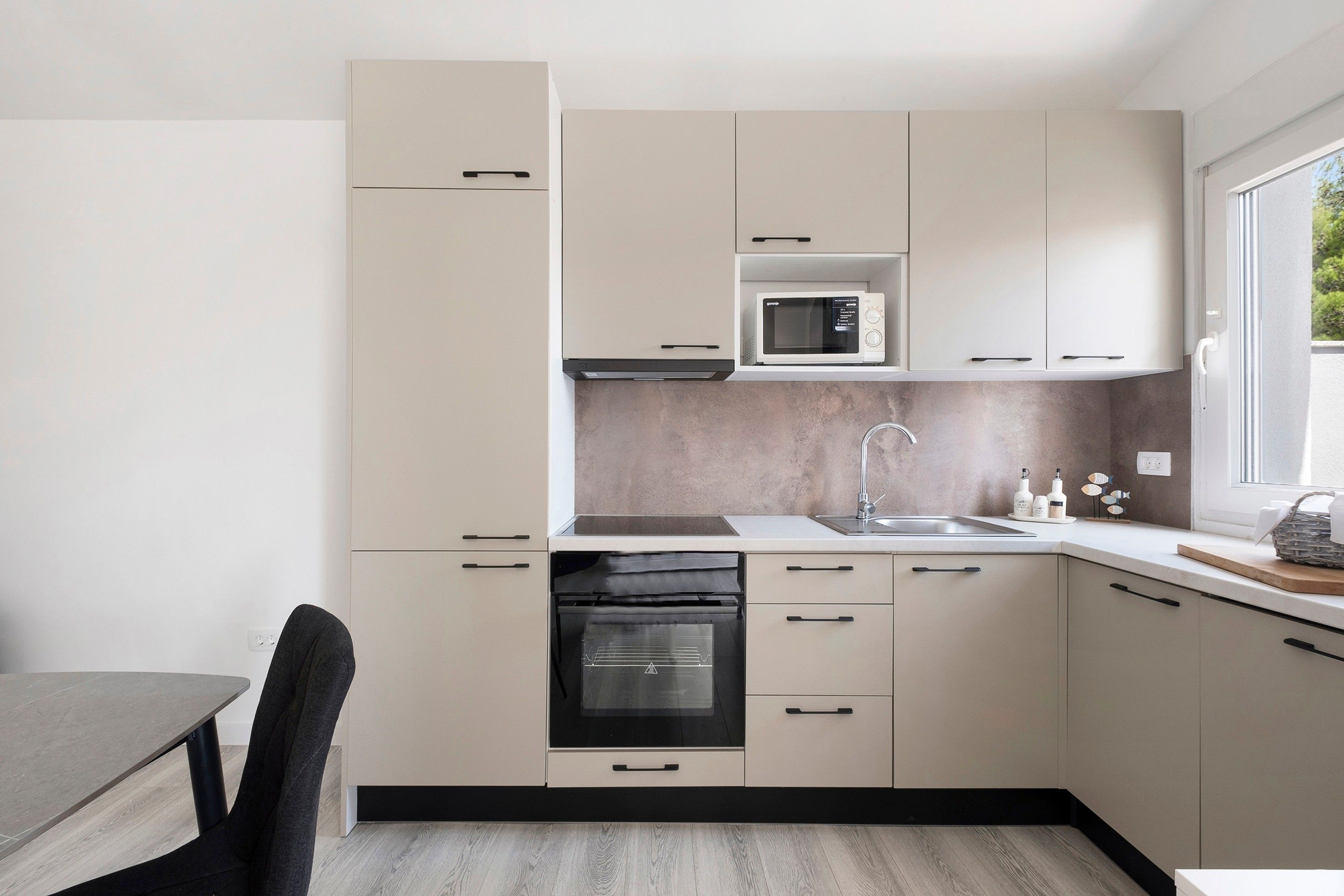 A modern kitchen with a built-in microwave, oven, and sink.