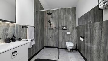 Een moderne badkamer met een marmeren wand, een witte wastafel, een zwarte handdoek en een douchegedeelte.