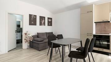 Un espacio de estar moderno con comedor, sofá y una obra de arte en la pared.