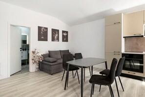 A modern living space with a dining area, sofa, and artwork on the wall.