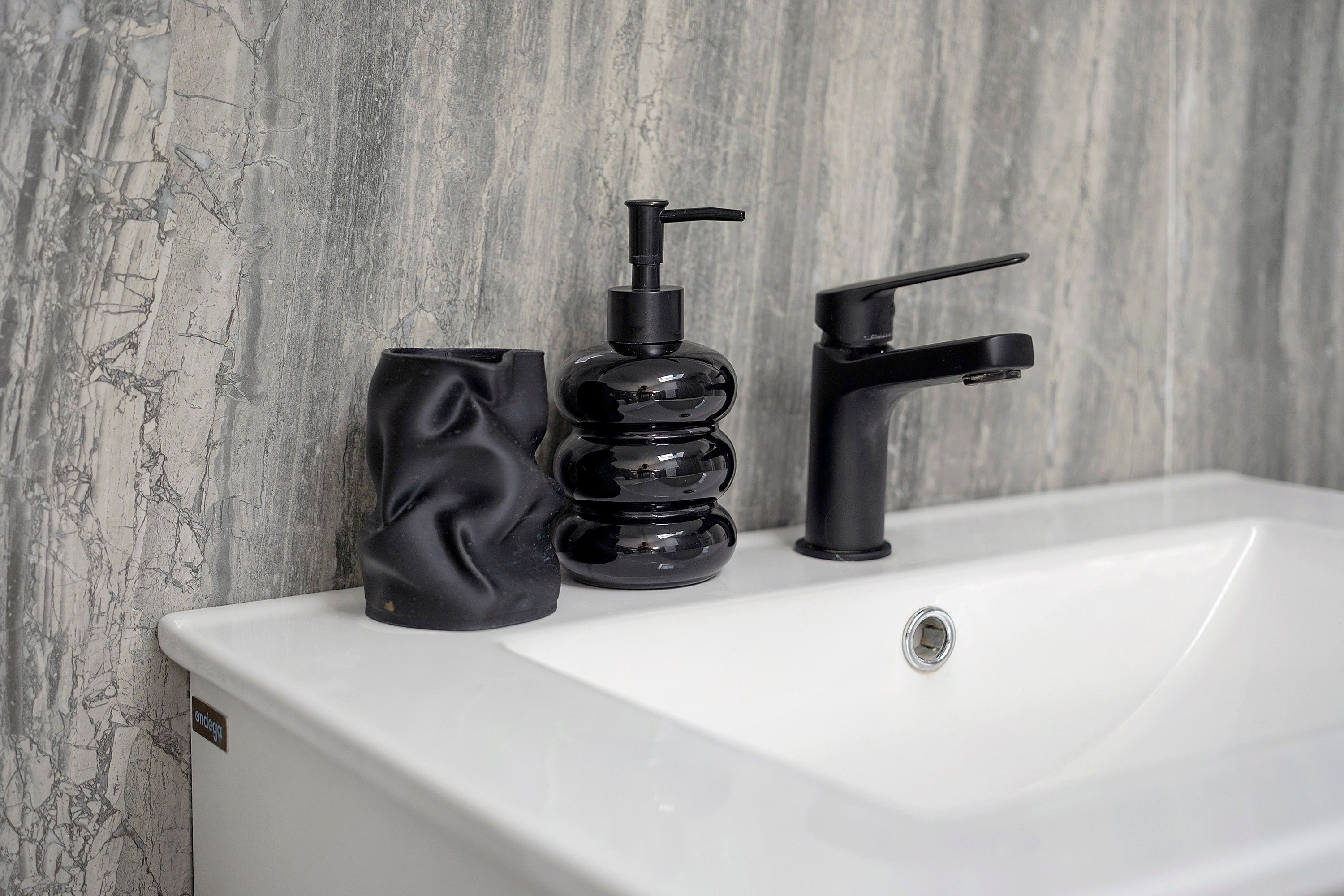 A bathroom sink with a modern faucet and a soap dispenser.