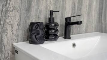 A bathroom sink with a modern faucet and a soap dispenser.
