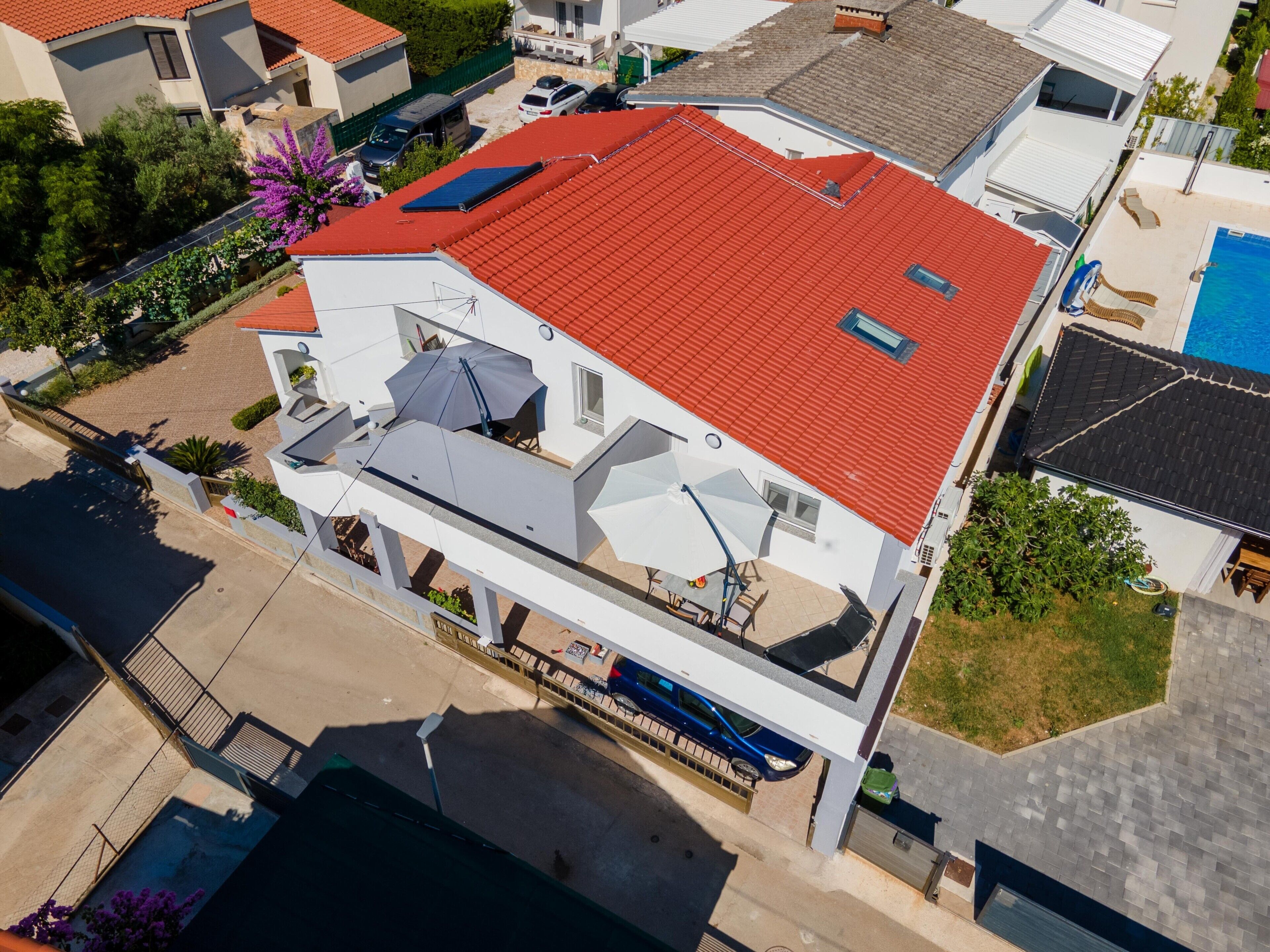 A two-story house with a red roof, a balcony, and a swimming pool.