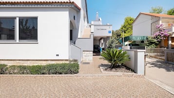A residential building with a tiled entrance, a small garden with a palm tree, and a visible satellite dish.