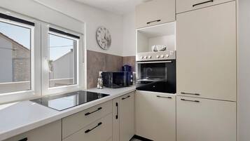 A modern kitchen with a built-in oven, microwave, and a window with blinds.