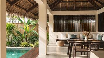 A modern interior with a pool, wooden deck, and a seating area with a sofa and table.