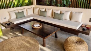 Ein modernes Wohnzimmer mit Ecksofa, Couchtisch und gewebten Poufs.