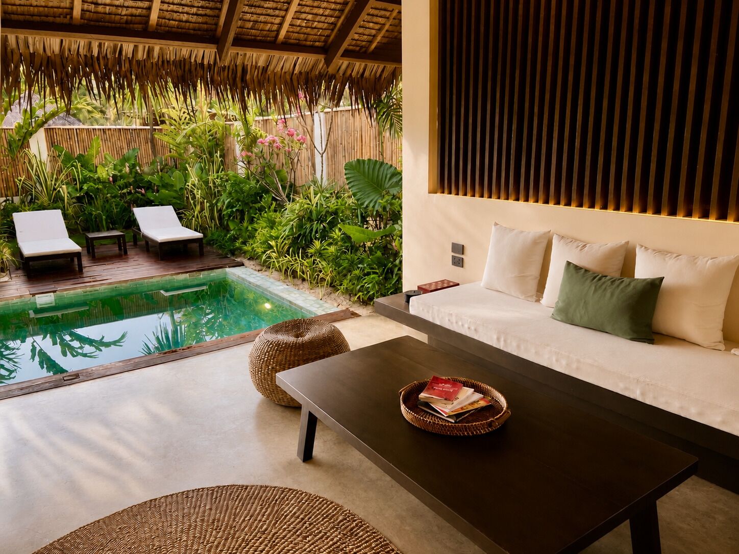 Un espace aménagé au bord de la piscine, avec des chaises longues, un canapé et une table basse.