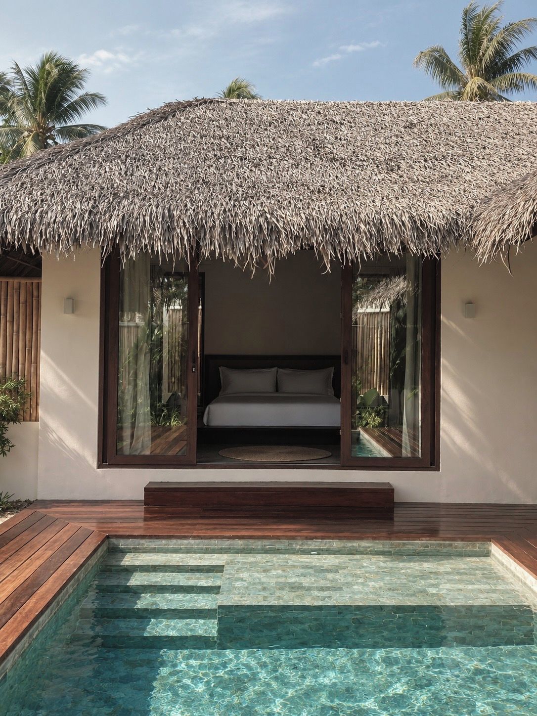 A modern villa with a thatched roof, a private pool, and a bedroom with a view.