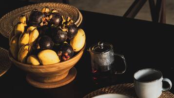 Een eettafel met een fruitschaal, een koffiepot en een kop.