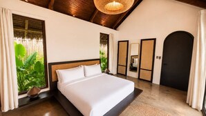 Ein Schlafzimmer mit einem großen Bett, einer Hängelampe, einem Spiegel und einer Tür.