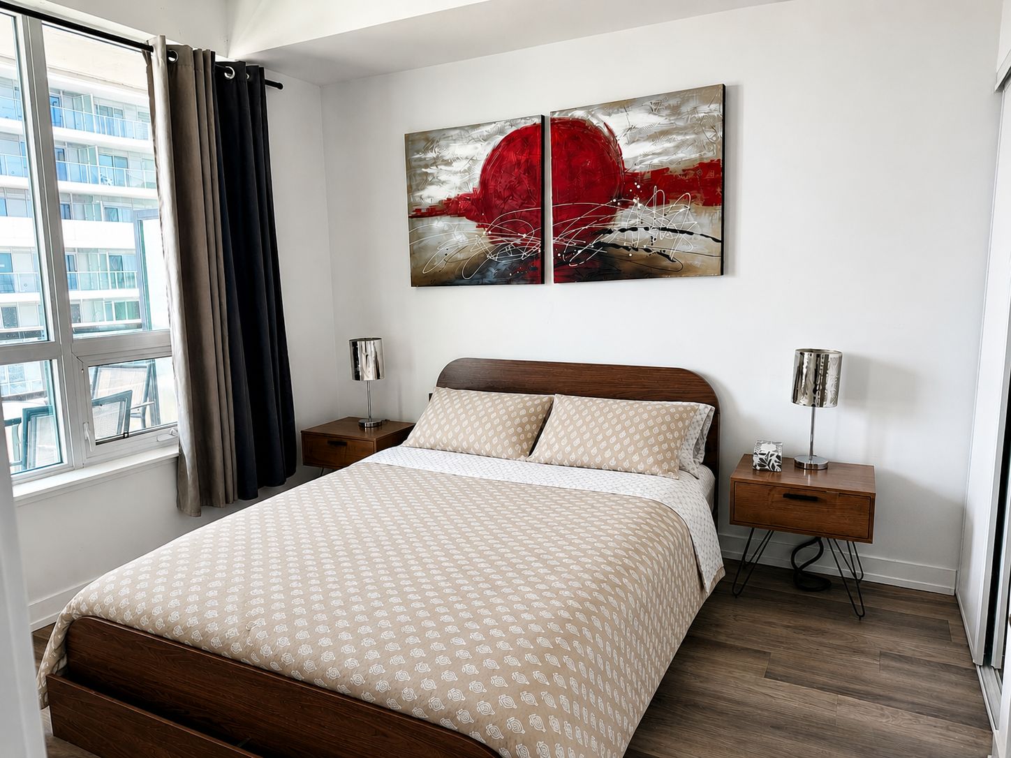 Une chambre d’hôtel moderne avec un grand lit, une table de chevet, une lampe et un tableau au mur.