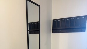 A room with a wall-mounted mirror, a light switch, and a calendar above a door.