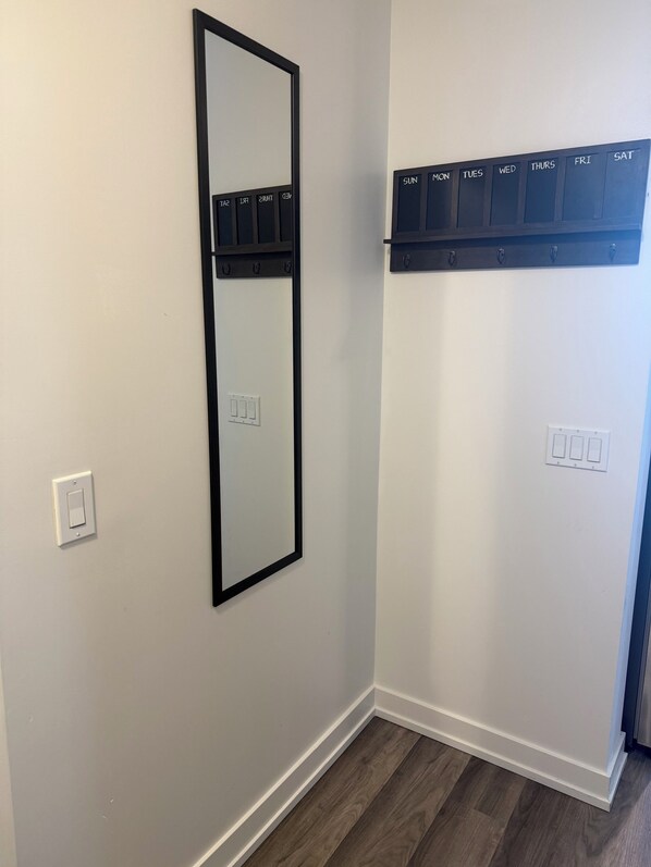 A room with a wall-mounted mirror, a light switch, and a calendar above a door.