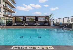 Une piscine avec une zone peu profonde délimitée, des chaises longues et un espace de repos abrité.