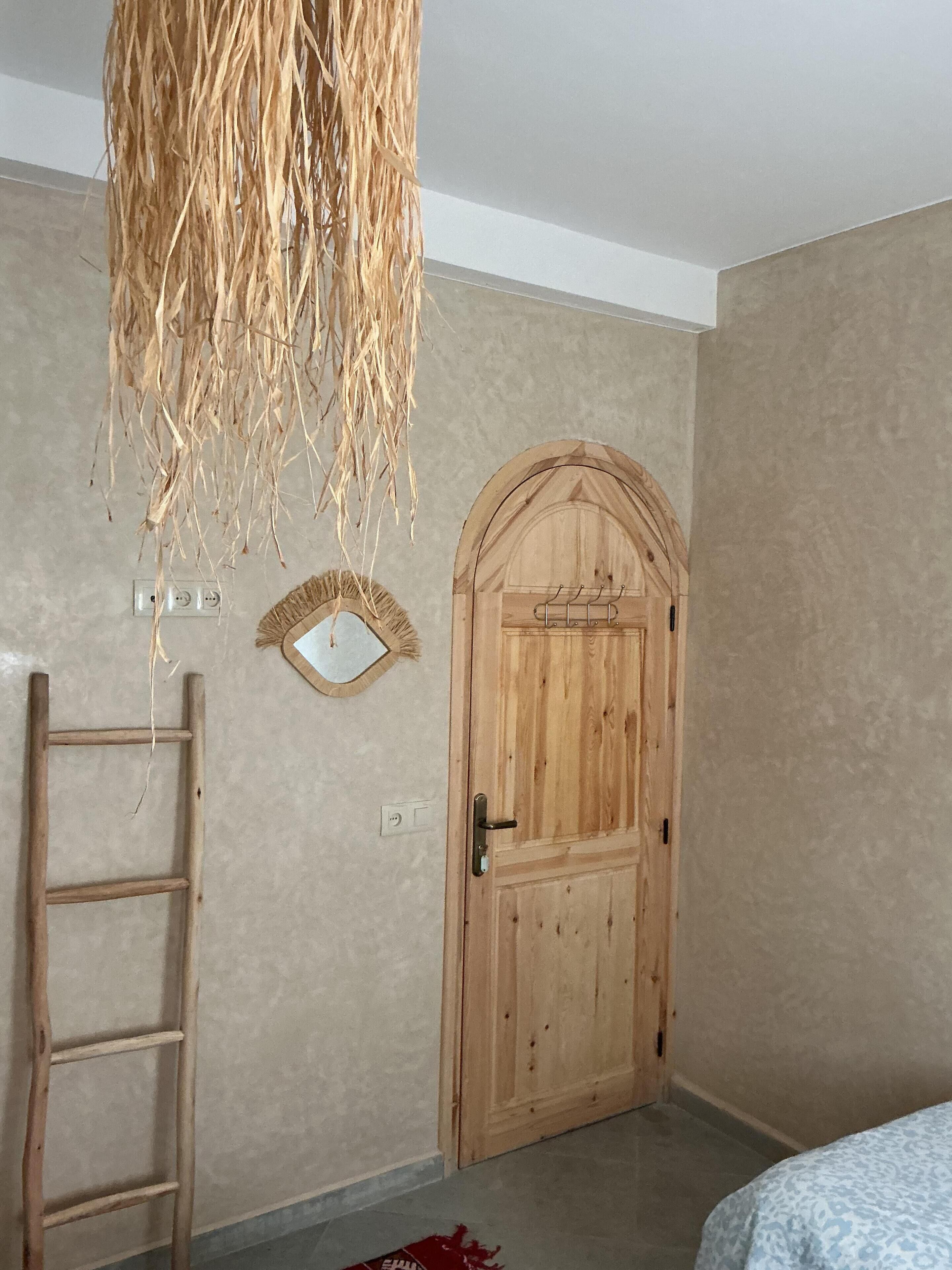 Une pièce dotée d’une porte en bois, d’une échelle et d’un élément décoratif suspendu.