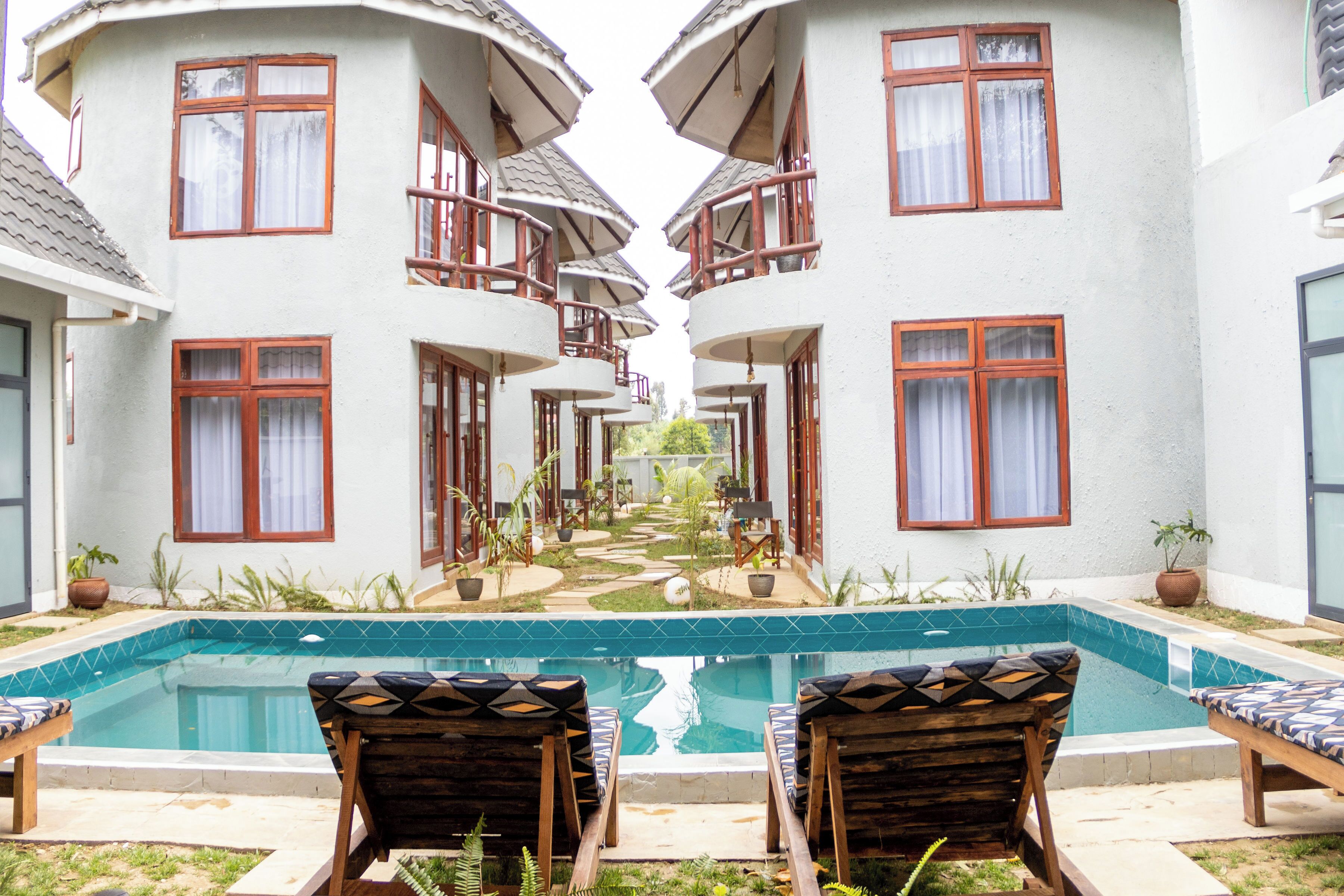 Uma área à beira da piscina com espreguiçadeiras, uma piscina e um edifício com várias varandas.