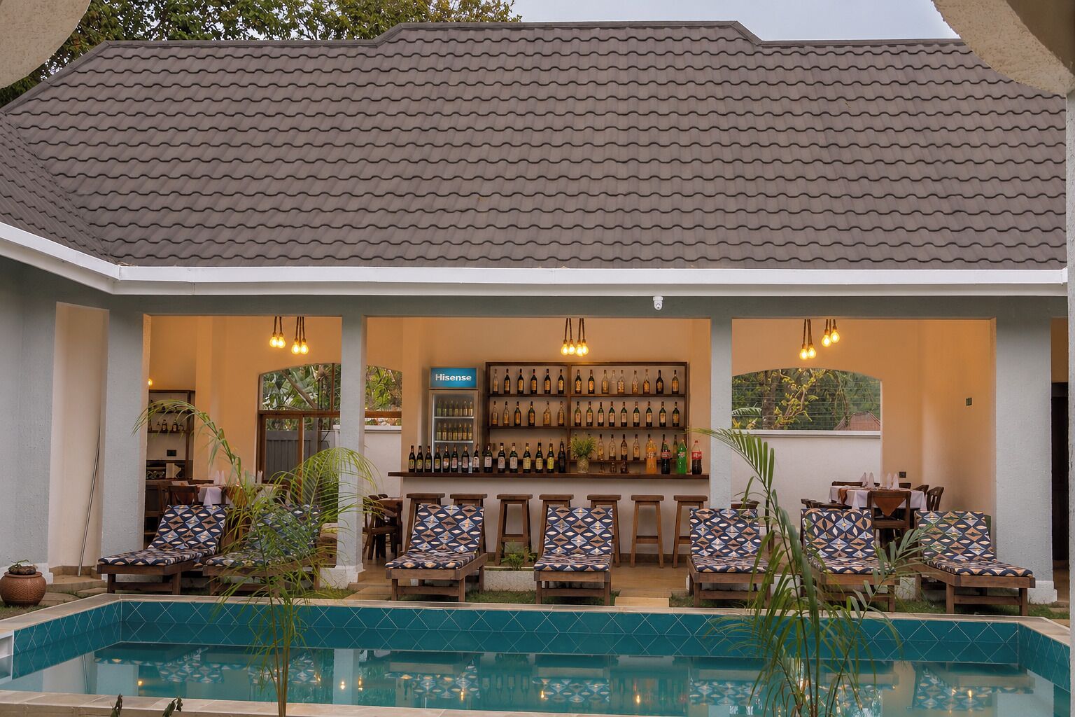 Zona de bar junto a la piscina con asientos y una exhibición de vinos.