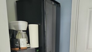 Pieni, käytännöllinen keittiönurkkaus, jossa on jääkaappi, kahvinkeitin ja mikroaaltouuni.