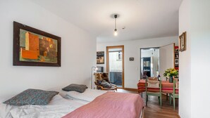 A bedroom with a bed, pillows, a painting, and a view of a balcony.