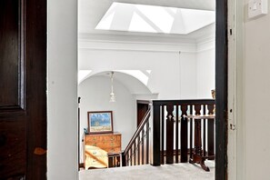 An interior view of a room with a staircase, a wooden dresser, and a framed picture on the wall.