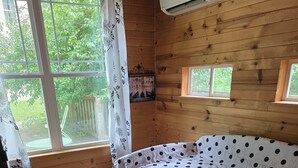 A wooden cabin room with a bed, a window, and a door. - Marvelous 2-bedroom cabin (Logan)