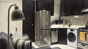 A modern kitchen with dark cabinets, a stainless steel refrigerator, a built-in oven, and a washing machine. - Discover the Comfort of Columbia University Area-2 (New York)