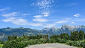 A mountainous landscape with a clear sky, a paved area, and dense forest. - Cabin apartment with mountain view (Morillon)