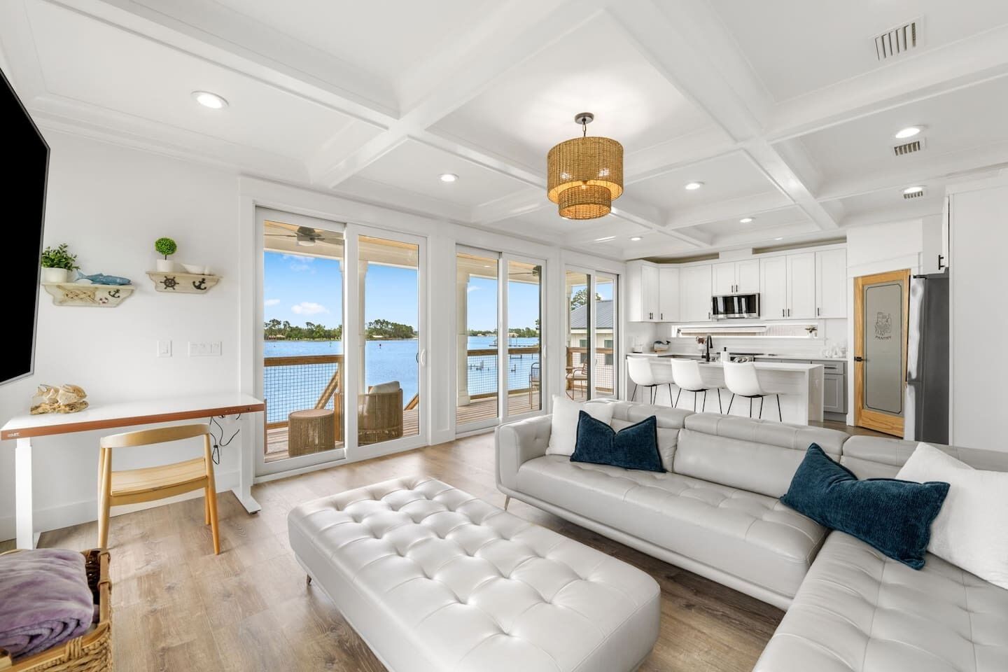 A spacious living area with a white sofa, a dining table, and a view of the water.