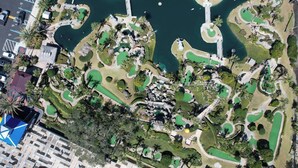 Vue aérienne d’un parcours de golf avec de nombreuses zones verdoyantes, des plans d’eau et des allées.