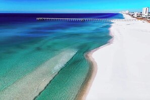 Una spiaggia con acque cristalline, un molo e edifici sullo sfondo.
