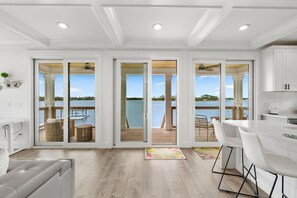 Un interno moderno con cucina, zona pranzo e ampie porte scorrevoli che si aprono su un patio con vista sul lago.
