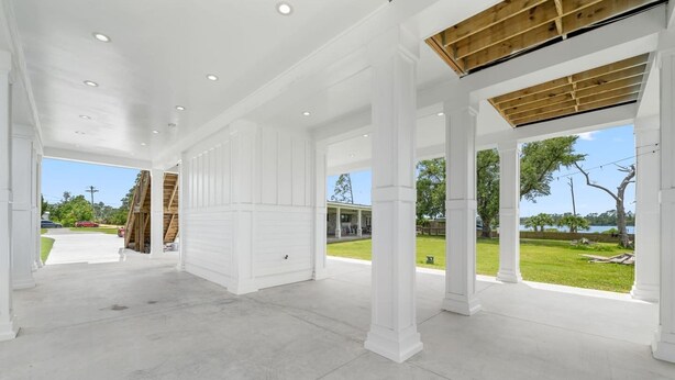 Un intérieur ouvert et spacieux, avec des colonnes blanches, un plafond haut et une vue sur l’extérieur.