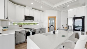 Une cuisine moderne avec des meubles blancs, un îlot central et un four encastré.