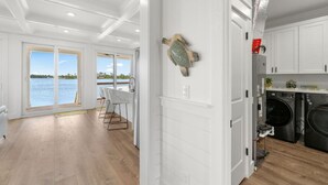 Une cuisine moderne dotée d’appareils électroménagers intégrés, un coin repas offrant une vue sur l’eau et une grande porte-fenêtre coulissante donnant sur un espace extérieur.