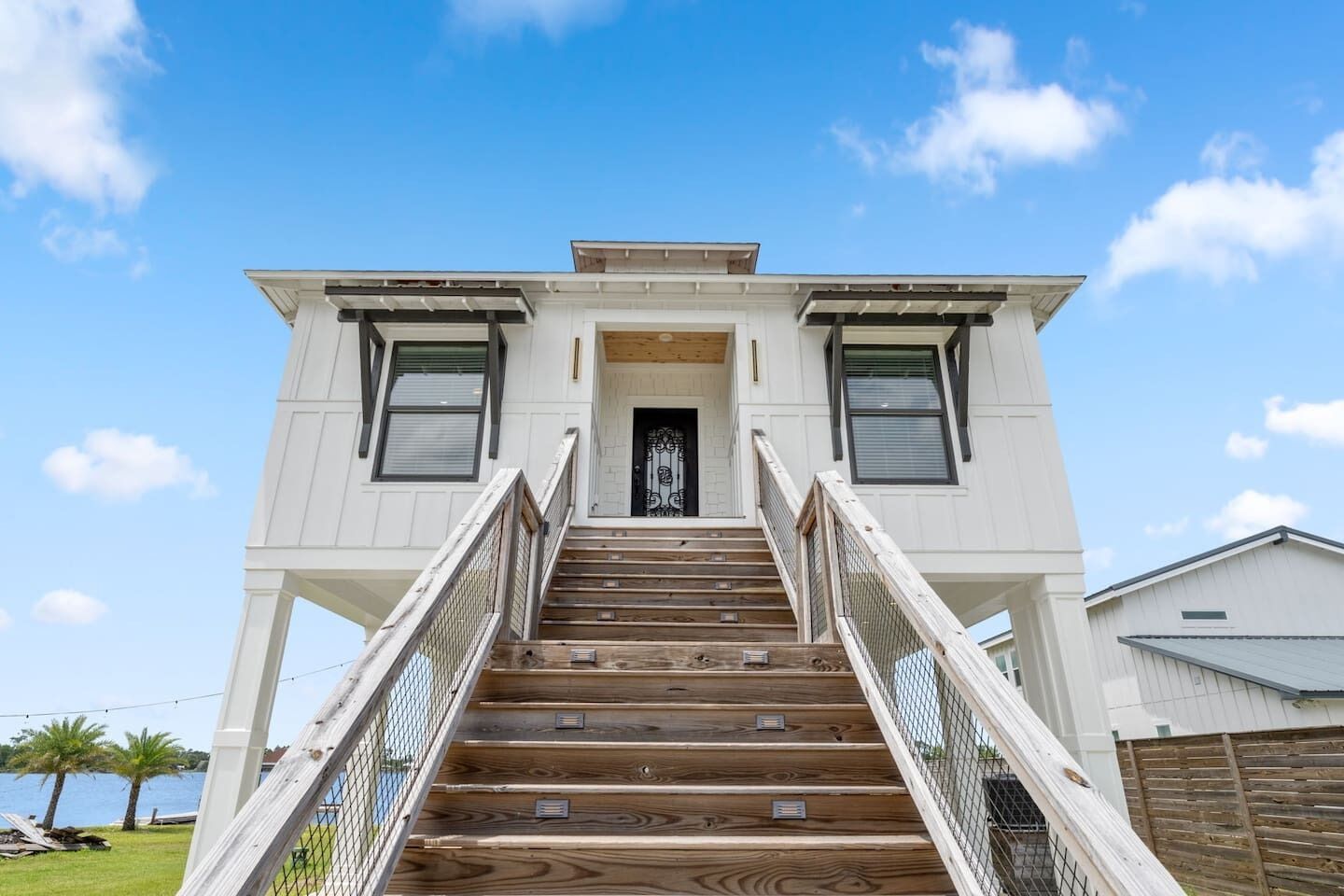 A two-story building with a wooden staircase leading to a door with a metal gate.