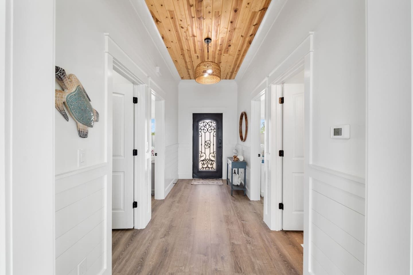 Un corridoio con pareti bianche, pavimento in legno e soffitto a vista con travi.