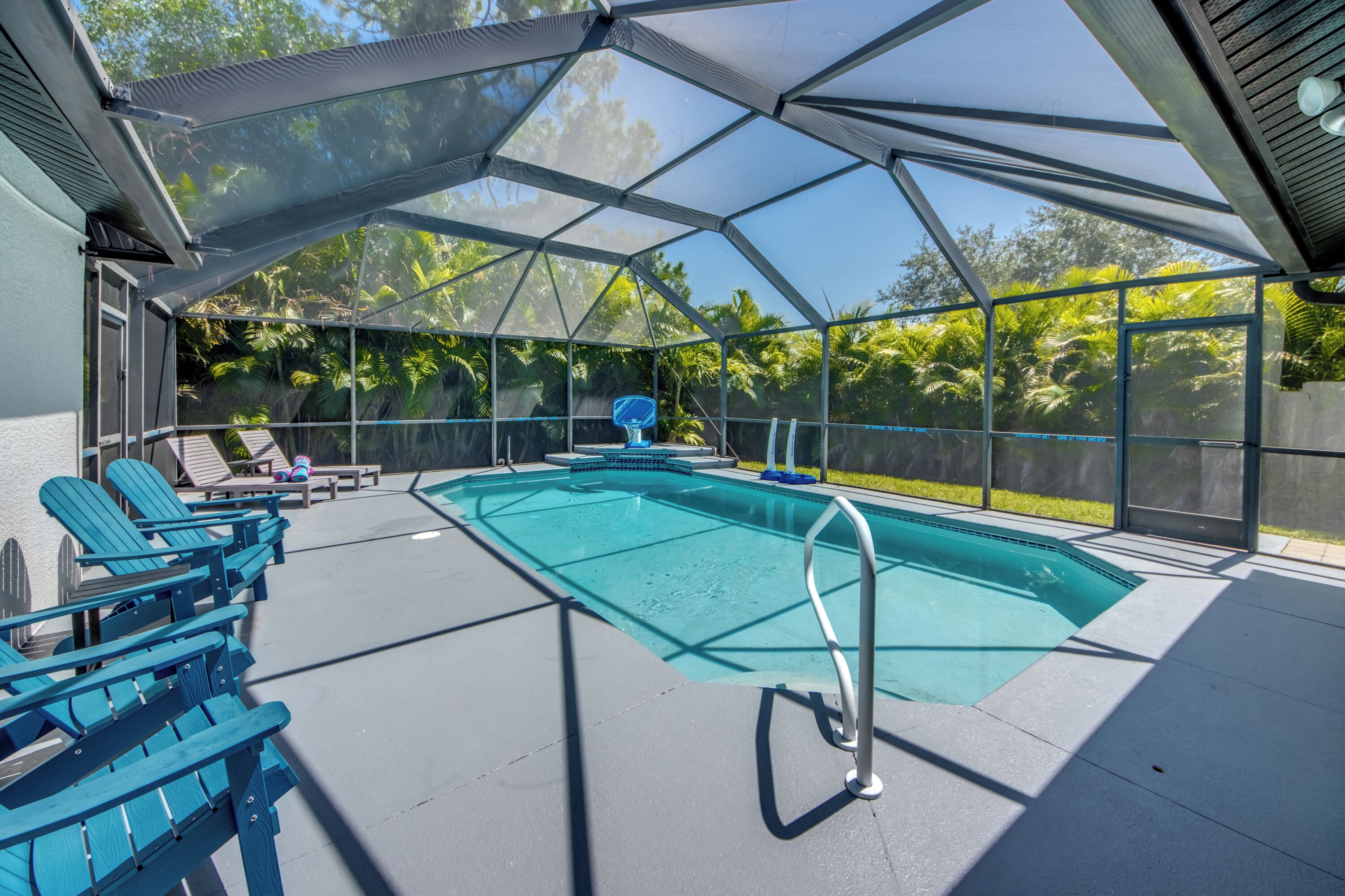 A covered outdoor swimming pool with lounge chairs and a pool ladder.