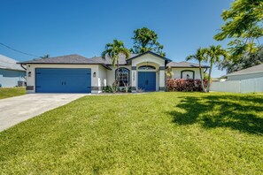 A two-story house with a garage, a front lawn, and palm trees. - Tropical Paradise-Salt Water Pool-Billiards-Pool Volley/Basket Ball-Sleeps 8 (Cape Coral)