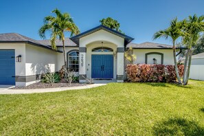 A residential house with a blue front door, a garage, and a well-maintained lawn. - Tropical Paradise-Salt Water Pool-Billiards-Pool Volley/Basket Ball-Sleeps 8 (Cape Coral)