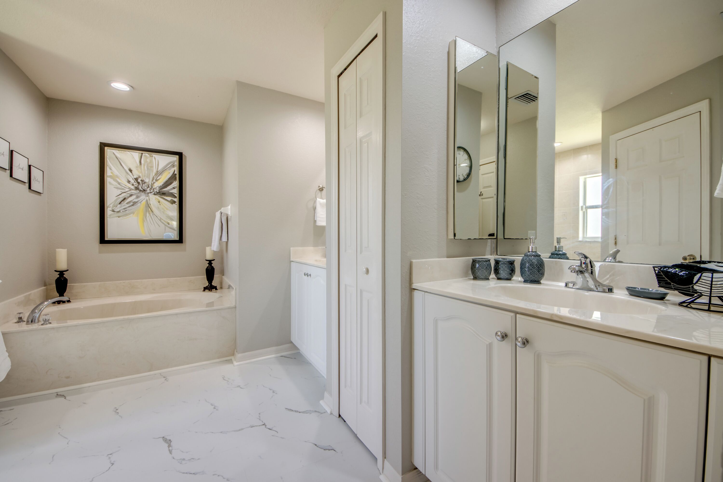 A bathroom with a bathtub, a large mirror, and a sink with a vanity.