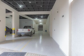 A parking garage with a white pickup truck, white walls, and a ceiling with a grid pattern. - Apartment w/ Gourmet Balcony | 180m from Perequê Beach (Porto Belo)
