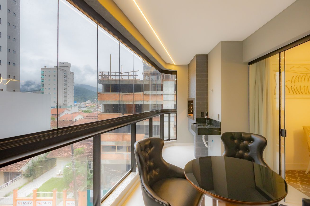 A modern balcony with a glass railing, a dining table, and two chairs.