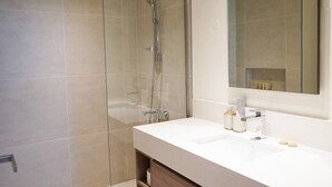 A modern bathroom with a glass shower enclosure, a white sink, and a large mirror. - Spacious 2 bedroom at Creek Edge - All Bills Included for long stay (Dubai)