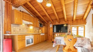 A wooden kitchen with a tiled backsplash, a built-in oven, and a dining area with a table set for two.